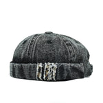 Black denim cap with distressed details on a white background