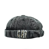 Black denim cap with distressed details on a white background