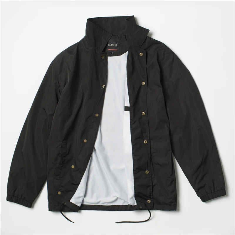 Black Nylon coach jacket laid flat open showing snap buttons and white lining