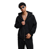 Person wearing a black hoodie and sunglasses on a beige background