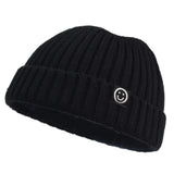 Black knit beanie with a smiley face logo on a white background