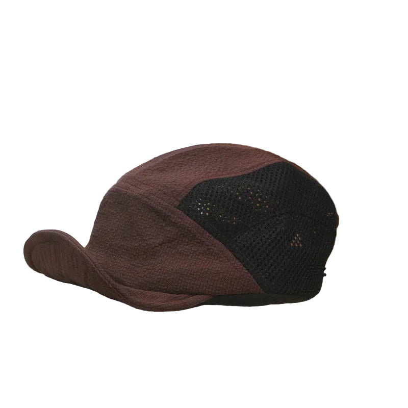 Burgundy and black cap on an open book with a wooden surface and white wall background