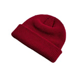 Red knit beanie on a magazine with yarn balls