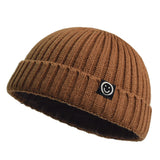 Camel knit beanie with a smiley face logo on a white background