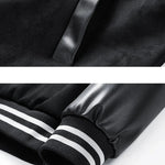 Close-up of a black jacket with a zipper and striped cuffs on a white background.