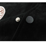 Close-up of a black jacket with buttons and a logo on a dark background