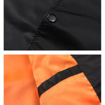 Close-up of black button on black fabric and orange fabric with black strip.