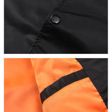 Close-up of black button on black fabric and orange fabric with black strip.
