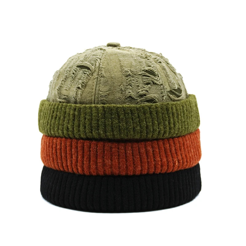 Stack of three knit hats in green, red, and black on a white background