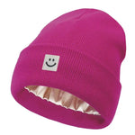 Fuchsia beanie with a smiley face label on a white background