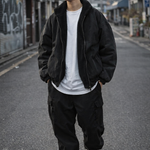 Person wearing a black jacket, white shirt, and black pants on an urban street.