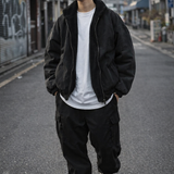 Person wearing a black jacket, white shirt, and black pants on an urban street.