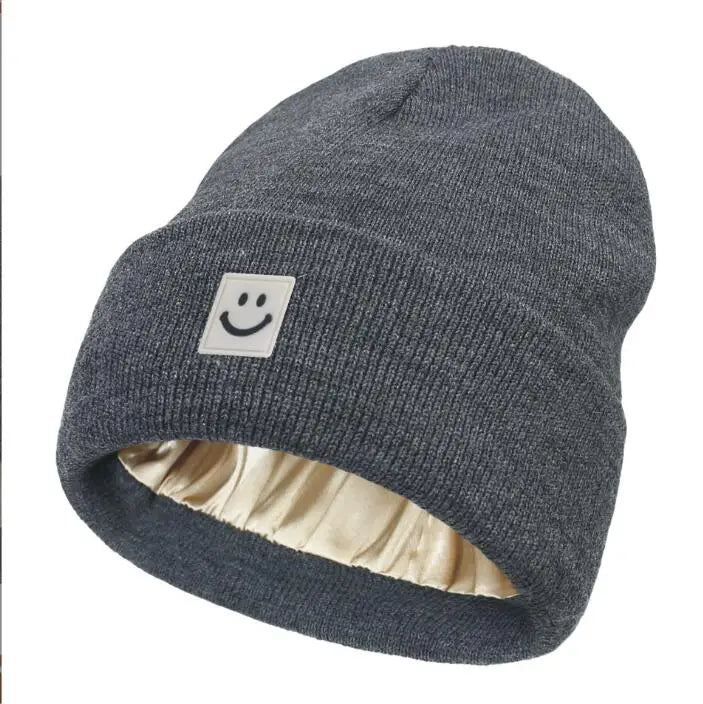 Gray knit beanie with a smiley face patch on a white background
