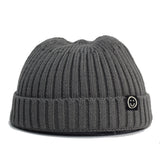 Gray knit beanie with a smiley face logo on a white background