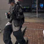 Person wearing a black jacket and pants on a city street at night.
