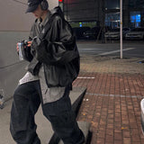 Person wearing a black jacket and pants on a city street at night.