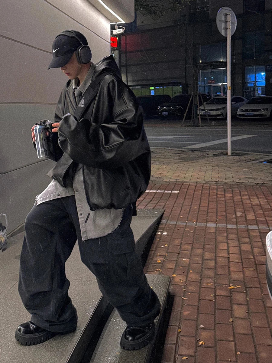 Person wearing a black jacket and pants on a city street at night.