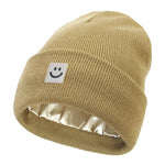 Khaki knit beanie with a smiley face label on a white background