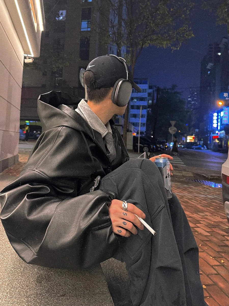 Person sitting on a street corner at night, wearing headphones and holding a cigarette.