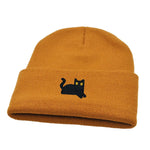 Mustard yellow beanie with a black cat embroidery on a white background