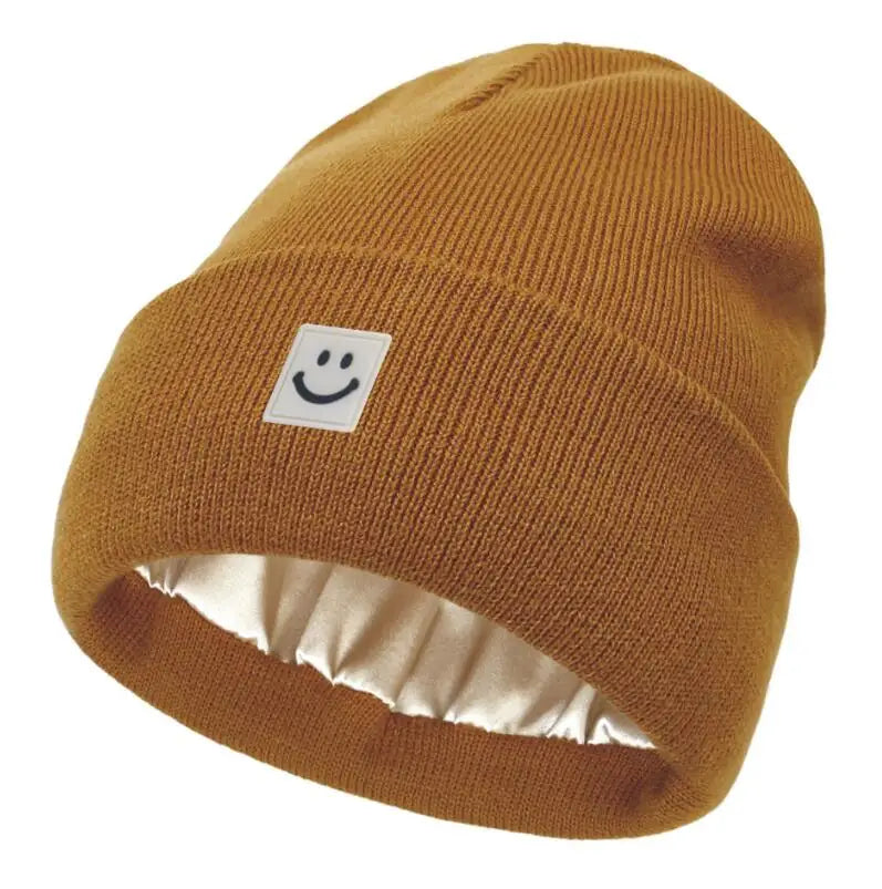 Mustard knit beanie with a smiley face label on a white background