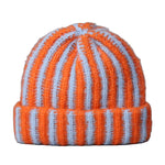 Knitted beanie with orange and white stripes on a gray background
