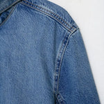 Close-up of turtleneck collar and vintage wash texture on women's oversized denim jacket