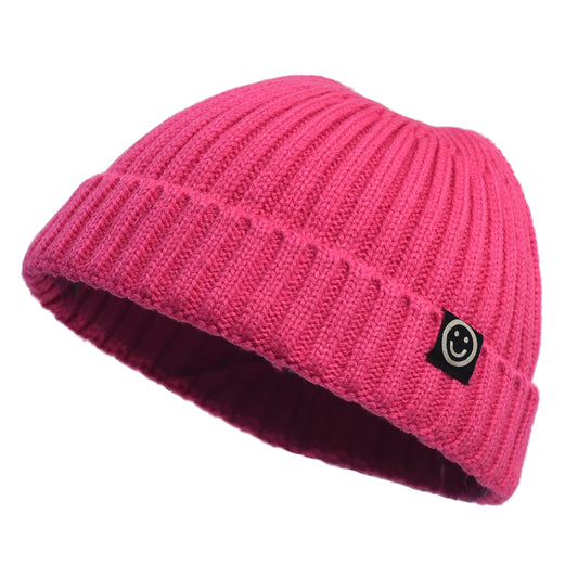 Pink knit beanie with a smiley face logo on a white background