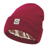 Red knit beanie with a smiley face label on a white background
