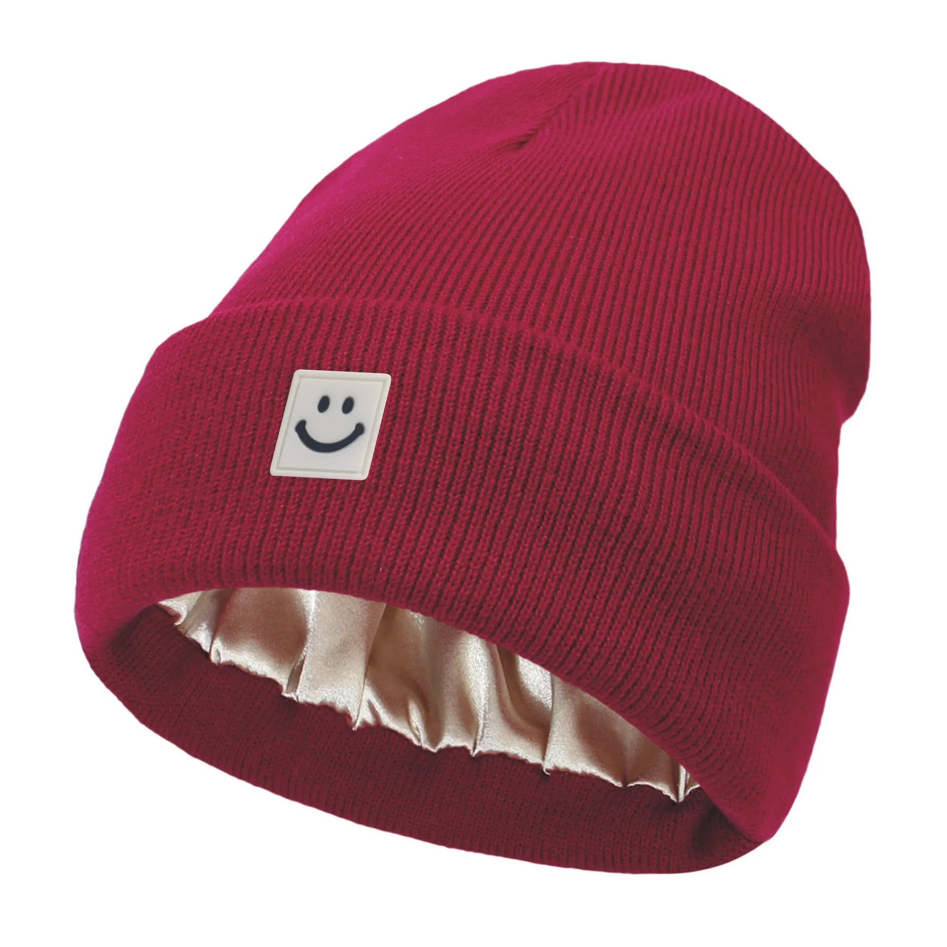 Red knit beanie with a smiley face label on a white background
