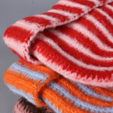 Stack of red, white, and orange striped fabrics on a gray background