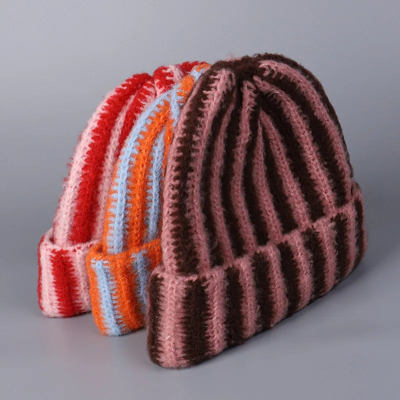 Three striped knit hats in red, orange, and brown on a gray background