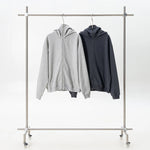 Two hoodies, one gray and one black, hanging on a metal clothing rack against a white background.