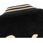 Close-up of a black garment with gold trim on a white background