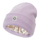 Violet knit beanie with a smiley face patch on a white background