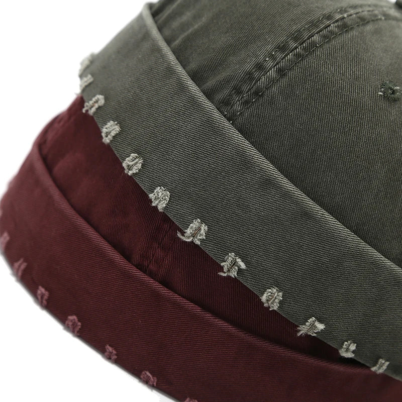 Two hats, one green and one maroon, with embroidered designs on a white background.