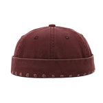 Wine red cap with embroidered details on a white background