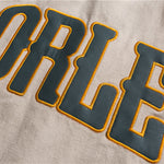 Beige Los Angeles varsity jacket close-up of embroidered leather lettering patch on sleeve