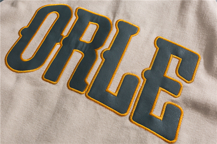 Beige Los Angeles varsity jacket close-up of embroidered leather lettering patch on sleeve