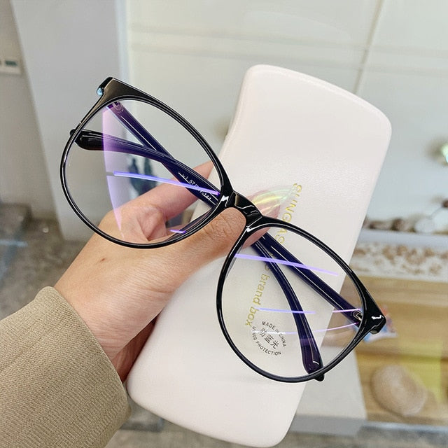 Black Blue light glasses held in hand showing round frame with glossy temple arms
