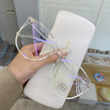 Clear Blue light glasses held in hand showing round frame and lens tint over case
