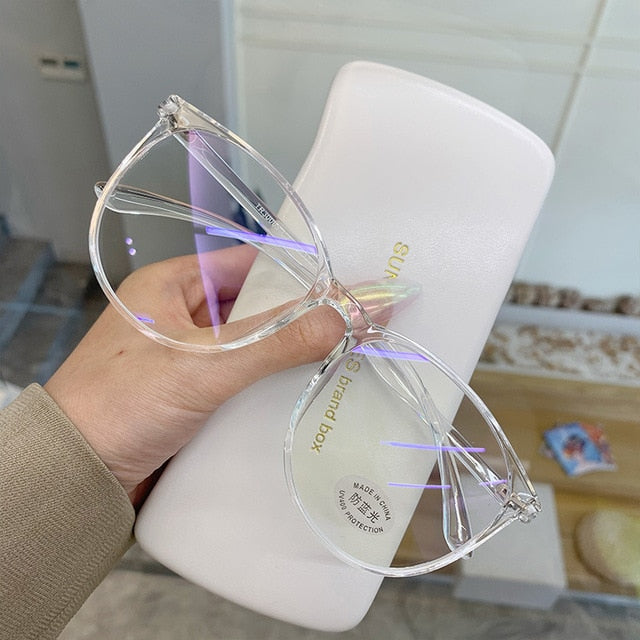 Clear Blue light glasses held in hand showing round frame and lens tint over case