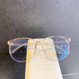 Light Pink Blue light glasses resting on book showing gradient tinted lenses