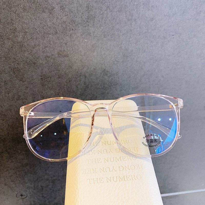 Light Pink Blue light glasses resting on book showing gradient tinted lenses