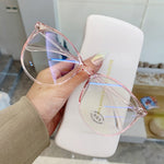 Pink Blue light glasses held in hand showing round frame with glossy fingernail