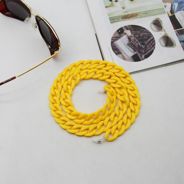 Yellow Glasses chain coiled flat lay next to sunglasses and magazine